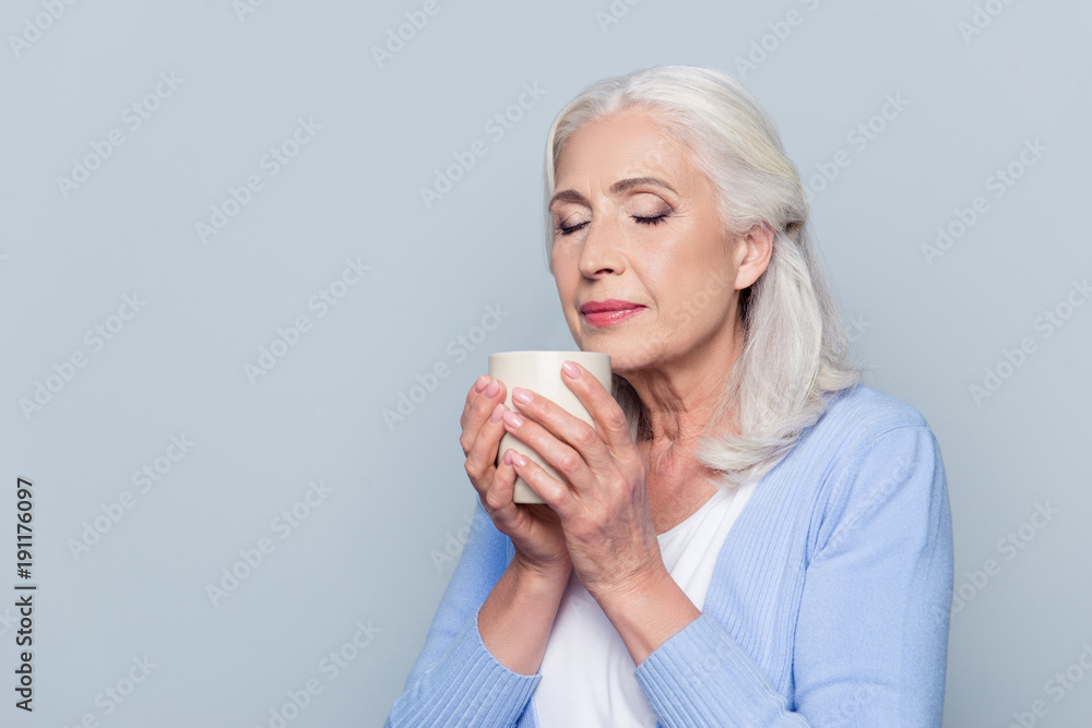 Close up portrait of happy satisfied joyful cheerful peaceful calm mature woman with grey hair and closed eyes, she is enjoying fresh coffee in her hands, isolated on gray background, copy-space Close up portrait of happy satisfied joyful cheerful peaceful calm mature woman with grey hair and closed eyes, she is enjoying fresh coffee in her hands, isolated on gray background, copy-space