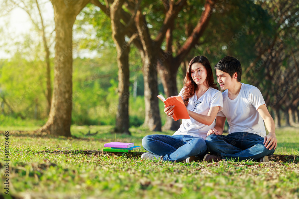 man and woman sitting and reading a book in park man and woman sitting and reading a book in park