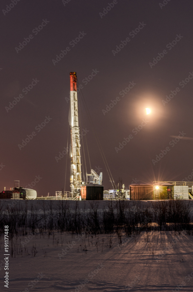 Obraz premium Oil rig during moon eclipse in the oilfield. Winter period. Oil and gas concept. Toned.