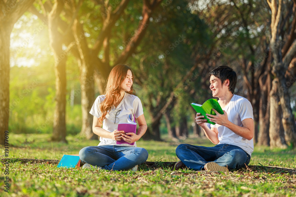 man and woman sitting and reading a book in park man and woman sitting and reading a book in park