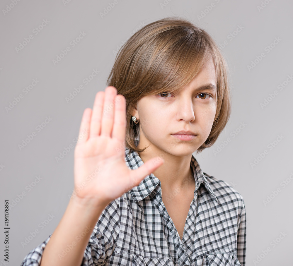 Close-up of emotional portrait of serious beautiful girl showing stop sign. Prohibition symbol. Child making stop gesture with her palm, on gray background. Close-up of emotional portrait of serious beautiful girl showing stop sign. Prohibition symbol. Child making stop gesture with her palm, on gray background.