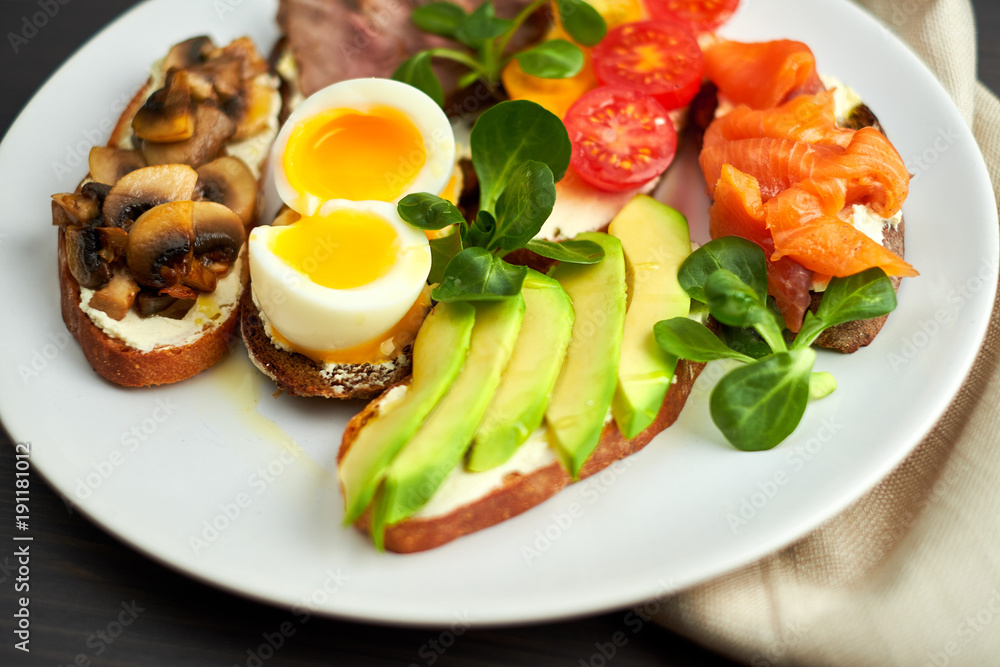 Bruschetta, assorted, different fillings, on plates with a soft-boiled egg in the middle Bruschetta, assorted, different fillings, on plates with a soft-boiled egg in the middle