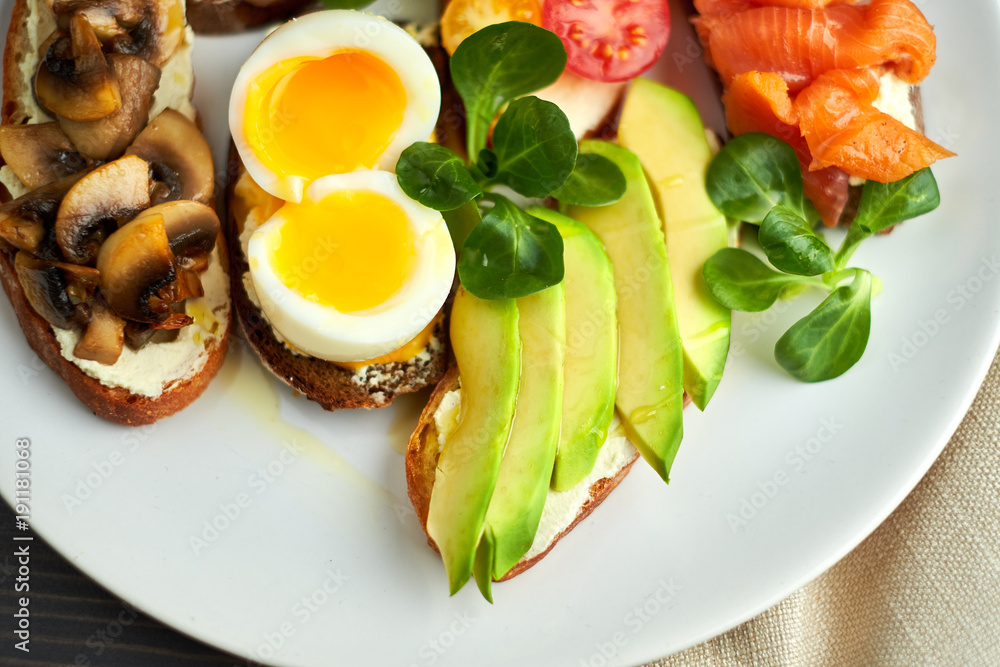 Bruschetta, assorted, different fillings, on plates with a soft-boiled egg in the middle Bruschetta, assorted, different fillings, on plates with a soft-boiled egg in the middle