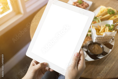 Top view A hand of woman holding tablet and touch screen tablet on table of lunch.