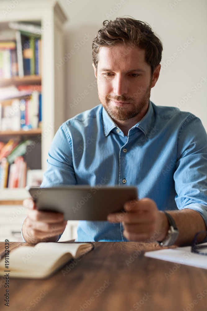 Smiling young man using a tablet while working from home Smiling young man using a tablet while working from home