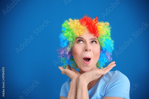 Young woman in funny disguise posing on color background. April fool's day celebration