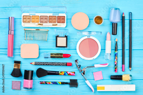 Beautiful composition of decorative cosmetics. Flat lay beauty items arranged on blue wooden background. Beauty fashion accessories.