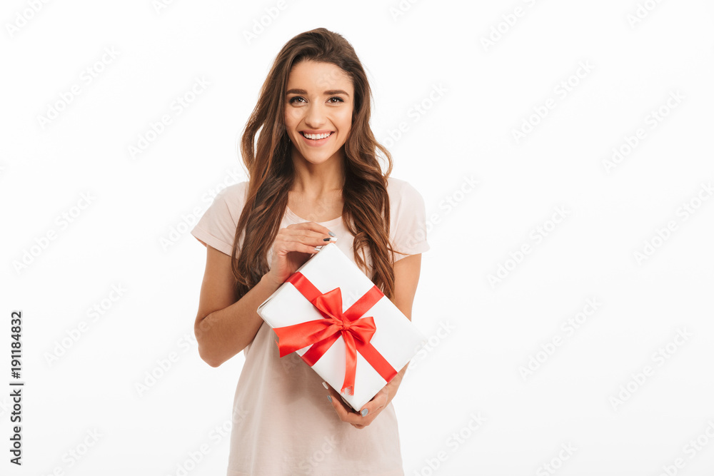 Smiling brunette woman in t-shirt holding gift box Smiling brunette woman in t-shirt holding gift box