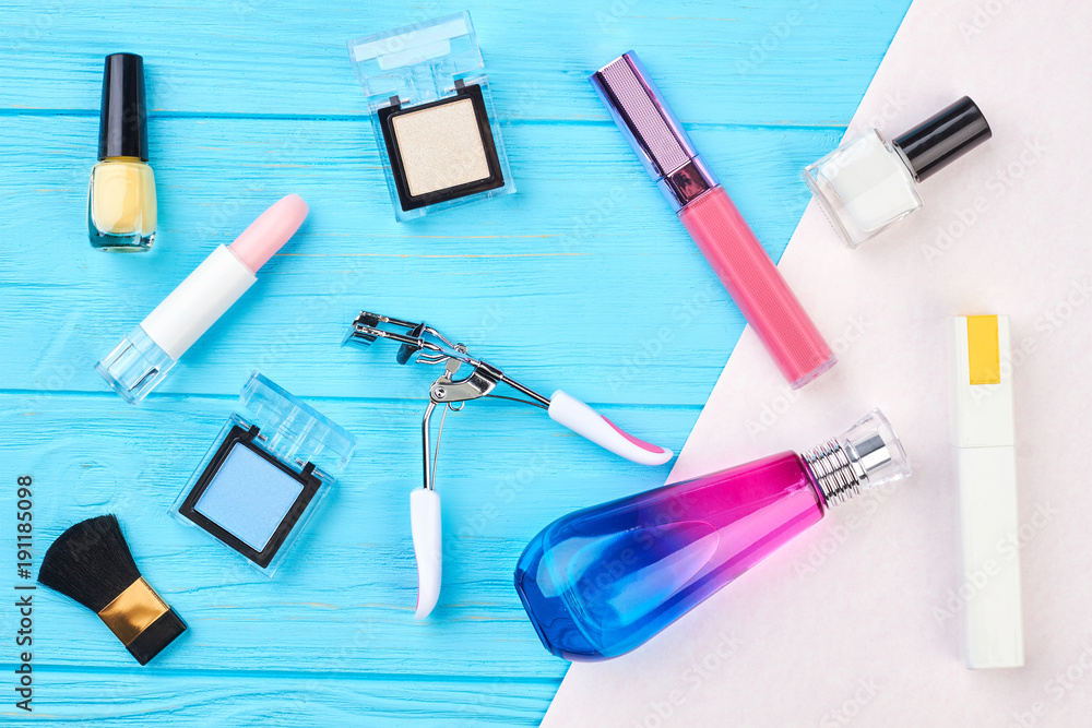 Decorative cosmetics set and tools. Eyelashes curler, perfume, nail polish, lipstick, eyeshadows on wooden background. Decorative cosmetics set and tools. Eyelashes curler, perfume, nail polish, lipstick, eyeshadows on wooden background.