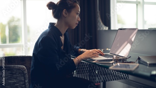 Young woman using a laptop while sitting at table photo