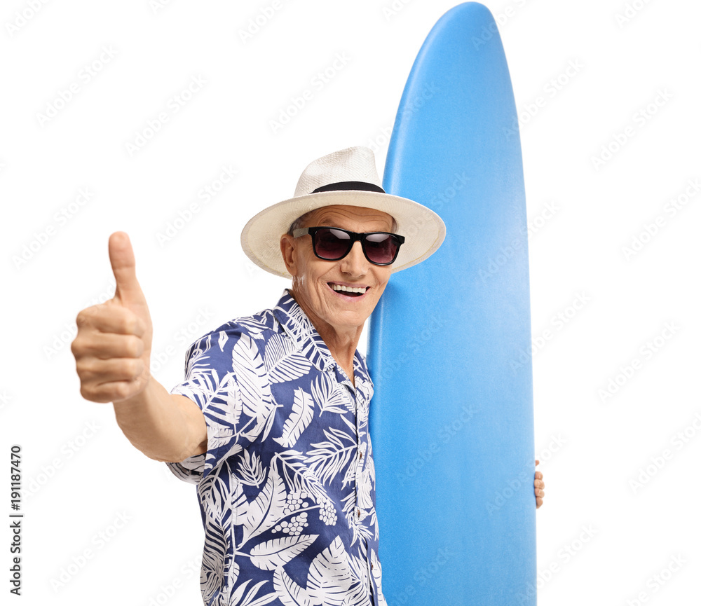Naklejka premium Elderly tourist holding a surfboard and making a thumb up sign