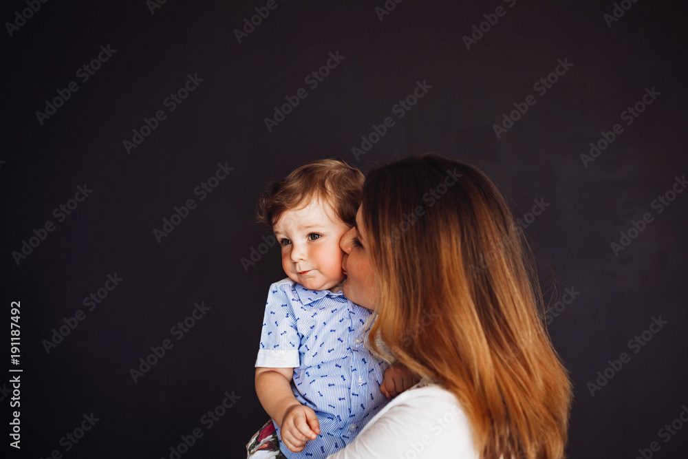 Mommy kisses her son tender standing in the dark room Mommy kisses her son tender standing in the dark room
