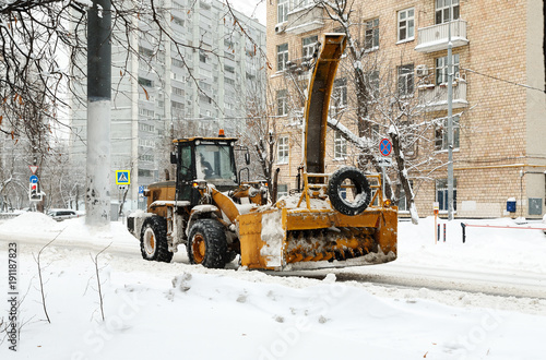 Big yellow snowblower cleans snow on the streets of a city photo