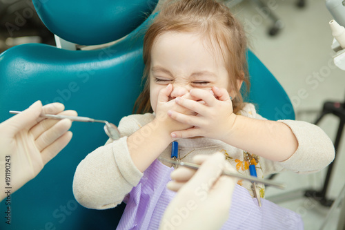 Child frightened by dentists instruments closes eyes and mouth