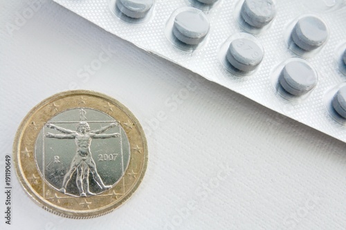 the obverse of the coin and blister pack of pills on wite background