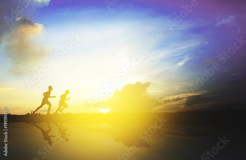 Silhouette of a boy running on sunset. Reflection of silhouette they on water.