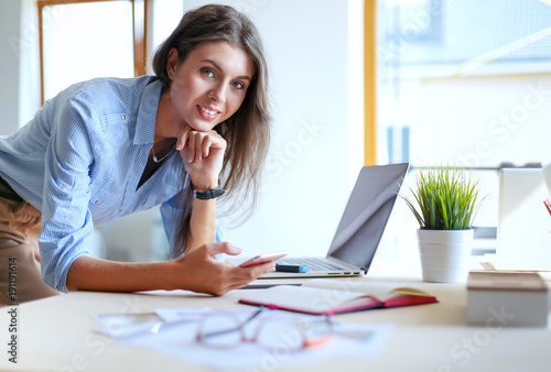 Beautiful young business woman sitting at office desk and talking on cell phone. Business woman