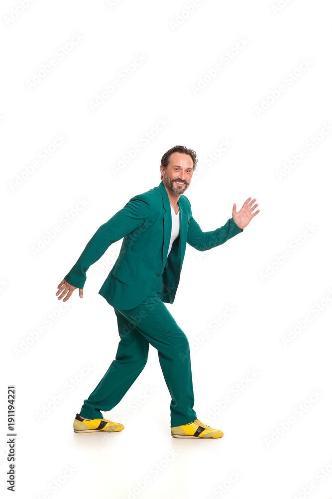 Cute man in green suit and yellow shoes. Imitating robot.