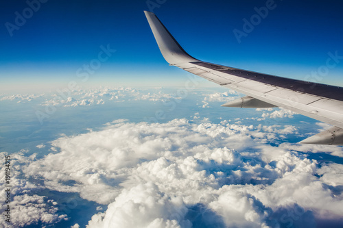 beautiful view from window porthole. wing of the plane on a background of clouds and blue sky. flight of airplane over city.