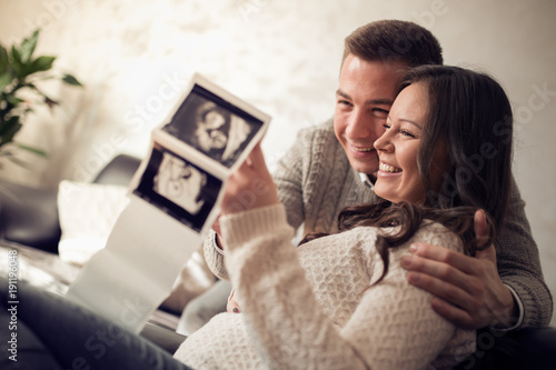 Fotografiet Young pregnant couple looking at ultrasound image