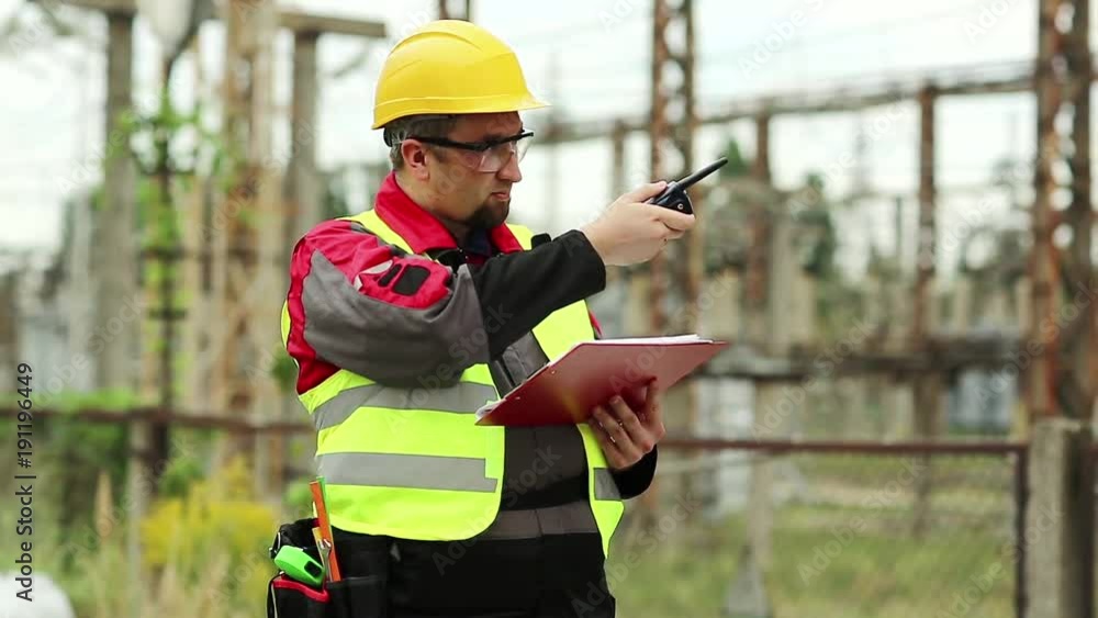 Electrician with portable radio transmitter on electric power station. Power engineering specialist on heat power plant communicates via radio station Electrician with portable radio transmitter on electric power station. Power engineering specialist on heat power plant communicates via radio station