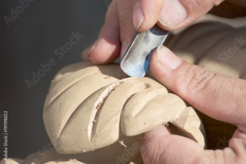 A beautiful wooden piece in the making. Closeup up picture of male hands, tools and the piece itself. photo