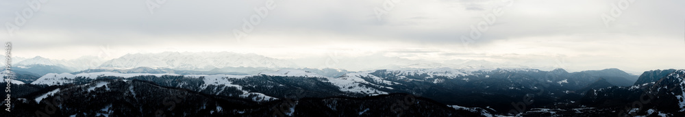 Panorama of the Caucasian ridge with clouds hanging on tops of mountains