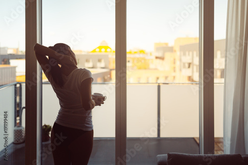 Картината върху платно Sleepy woman stretching,drinking a coffee to wake up early in the monday morning sunrise