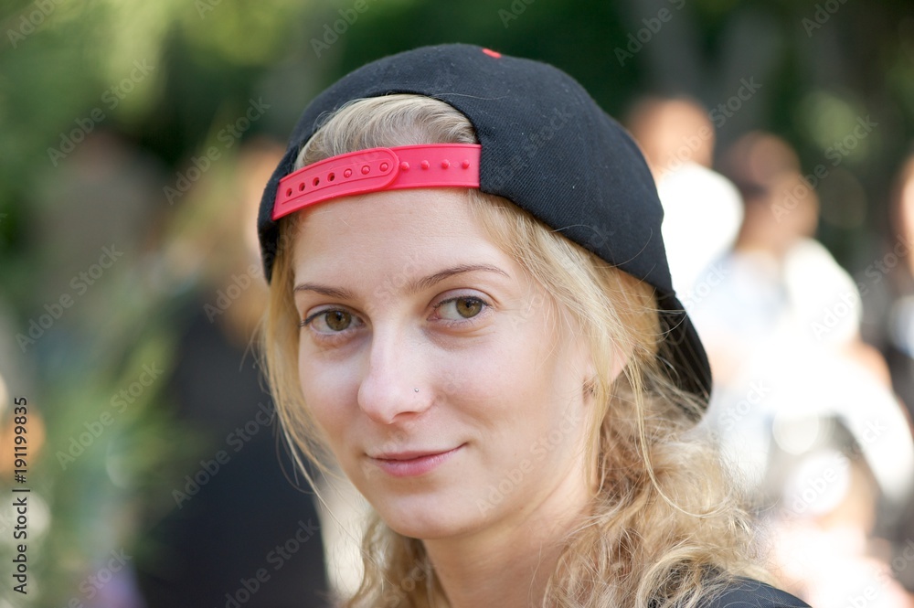 east Humanistic construction A young blonde woman wearing a black baseball cap backwards looking  straight into the camera. Stock Photo | Adobe Stock