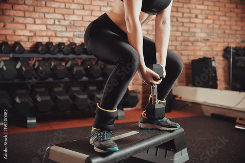 Young sportive woman exercising in gym using step platform with weighting. Concept of weight loss