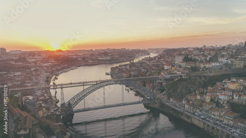 Aerial long exposure of the iconic Dom Luis I bridge at sunset designed by Gustav Eiffel crossing the Douro River,historical Ribeira and Se District in Porto,Portugal.Unesco World Heritage Site