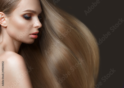 Beautiful blond girl with a perfectly smooth hair, classic make-up. Beauty face. Picture taken in the studio on a white background.