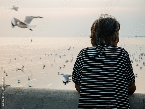 back of old women standing alone at the sea and looking for some thing.