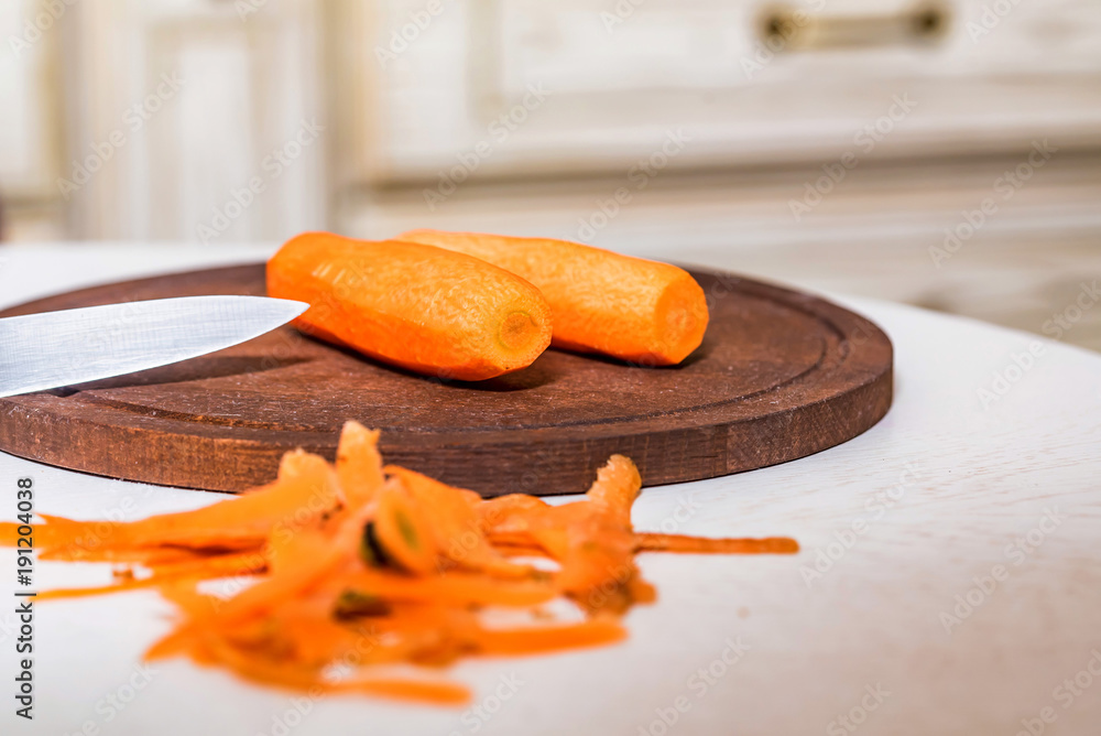 Peeled carrots and their peel on wooden board Peeled carrots and their peel on wooden board