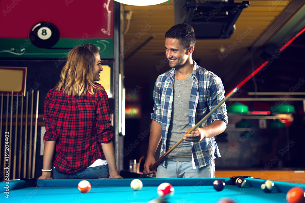Fototapeta premium Couple dating, flirting and playing billiard in a pool hall