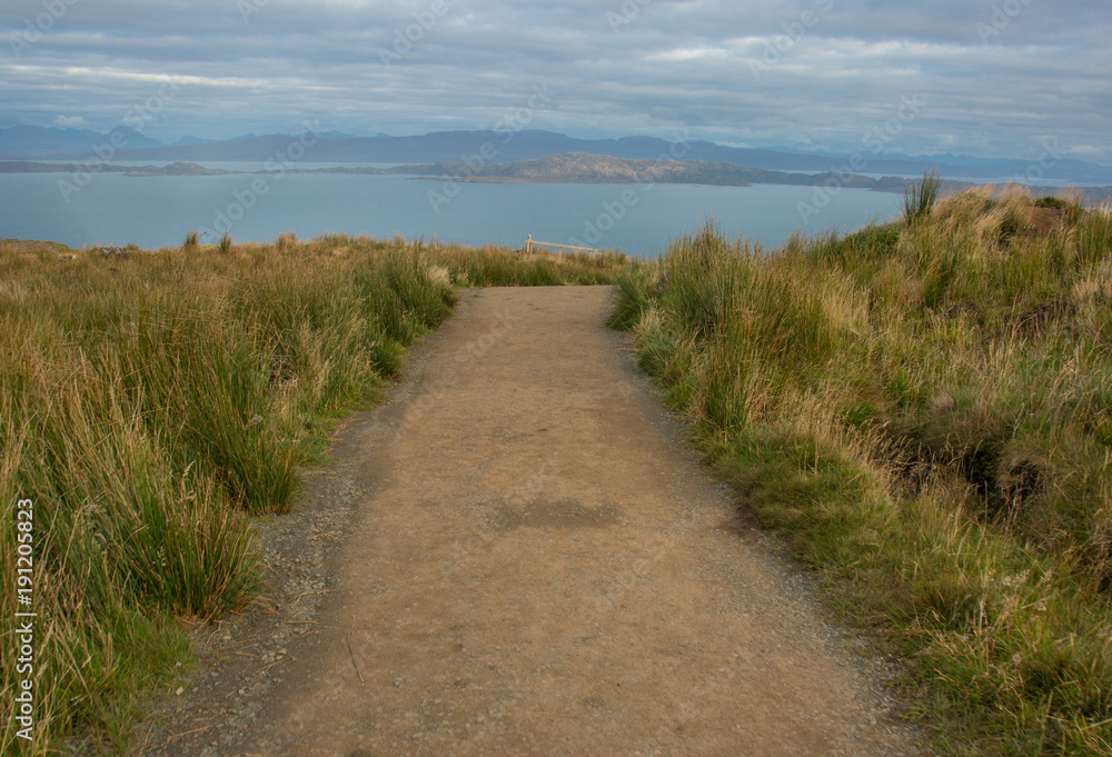 A hiking path over a Scottish mountain on the Isle of Skye looking over water towards other islands and mountains. A hiking path over a Scottish mountain on the Isle of Skye looking over water towards other islands and mountains.