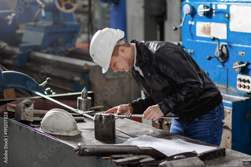 a young successful engineer makes a measurement of the details of the mechanism