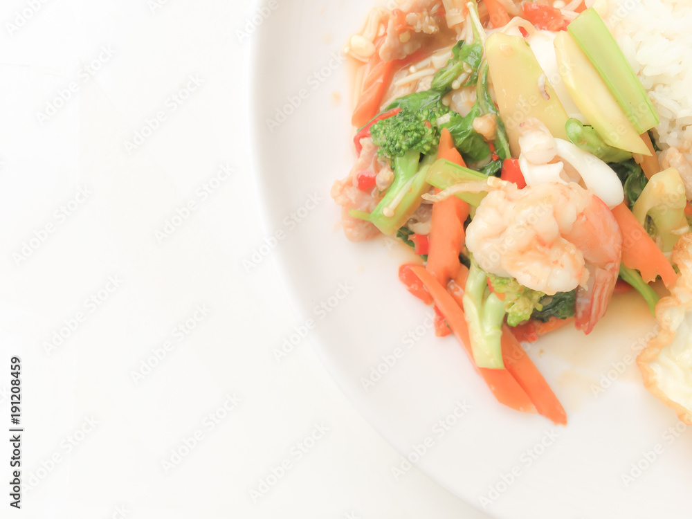 Fried Savory sauteed mixed vegetables with shimp and fried egg served with rice in white dish on white background as Thai homemade meal or recipe in the restaurant. Thai style food. Fried Savory sauteed mixed vegetables with shimp and fried egg served with rice in white dish on white background as Thai homemade meal or recipe in the restaurant. Thai style food.