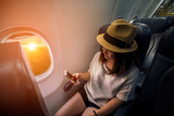 Young asian woman traveler using smartphone in airplane with happiness and relaxing