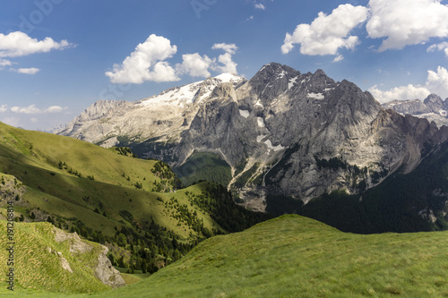 Green hills of the Dolomites against the background of the Marmolada massif.