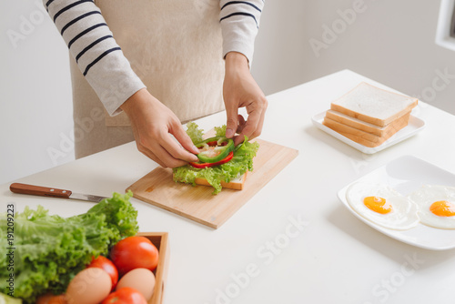 Hands of man prepare sandwich at home.