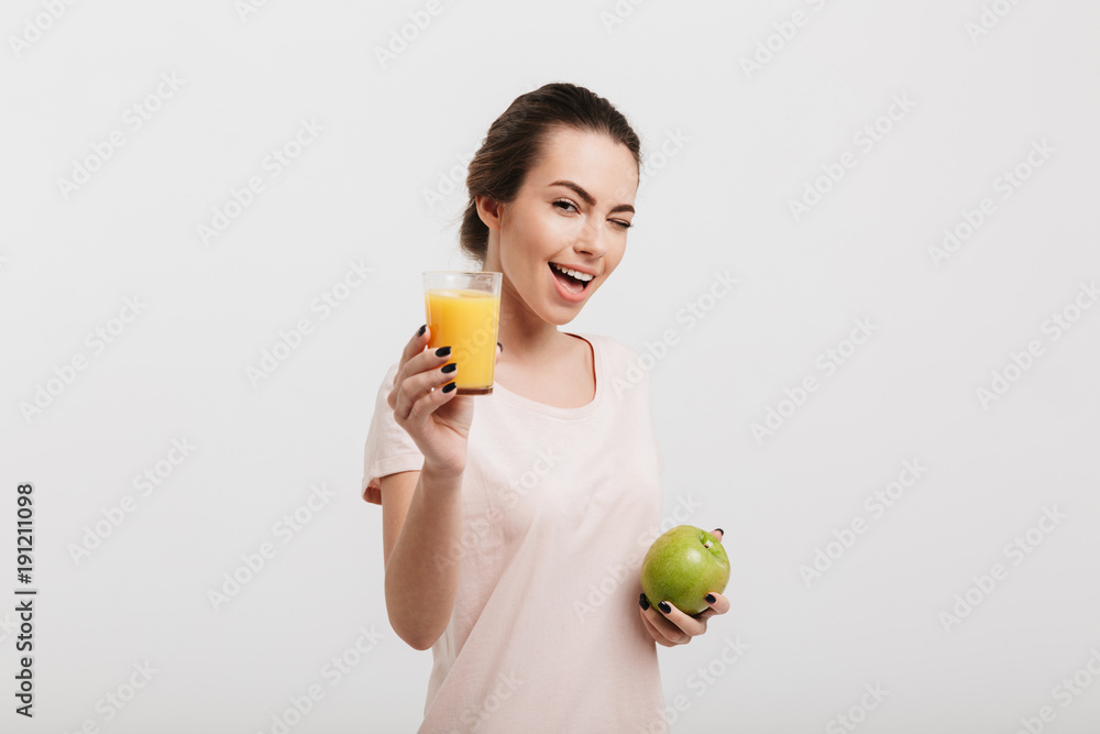 beautiful girl winking and holding glass of juice and apple isolated on white beautiful girl winking and holding glass of juice and apple isolated on white