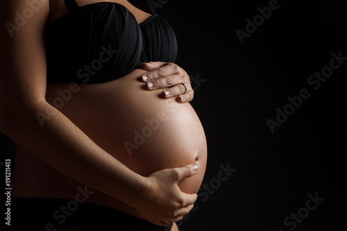 Femme enceinte avec les mains sur le ventre en studio photo