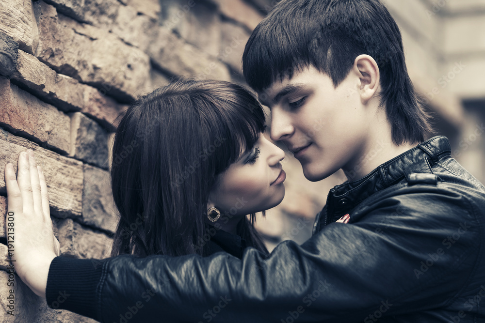 Happy young fashion couple in leather jackets at the brick wall Happy young fashion couple in leather jackets at the brick wall