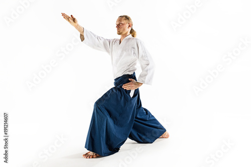 Aikido master practices defense posture. Healthy lifestyle and sports concept. Man with beard in white kimono on white background.