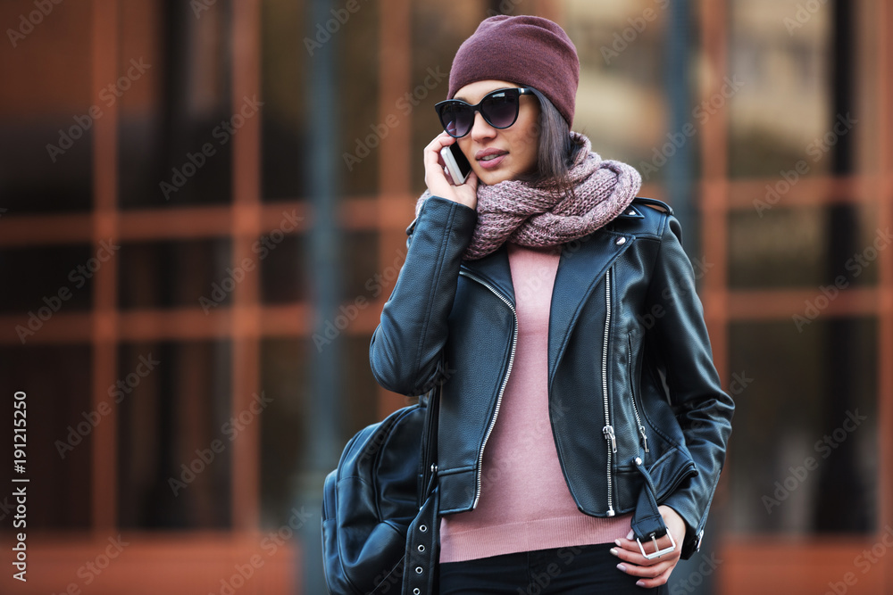 Young fashion woman in black leather jacket using cell phone in city street Young fashion woman in black leather jacket using cell phone in city street