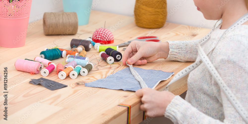 girl sews doll clothes, Child sewing  - obrazy, fototapety, plakaty 