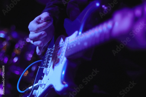 artist Guitarist hand play electricity guitar on concert stage with blue light, Practicing in playing . song entertainment and music instrument.