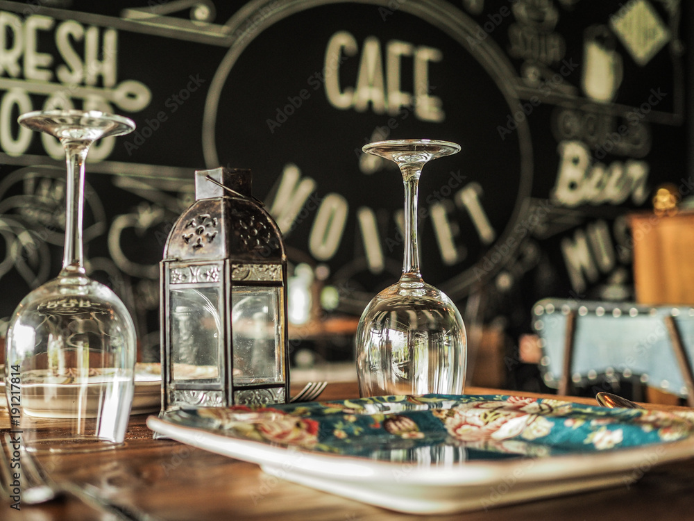 romantic plate setting in a cute vintage cafe on a wooden table with wine glasses