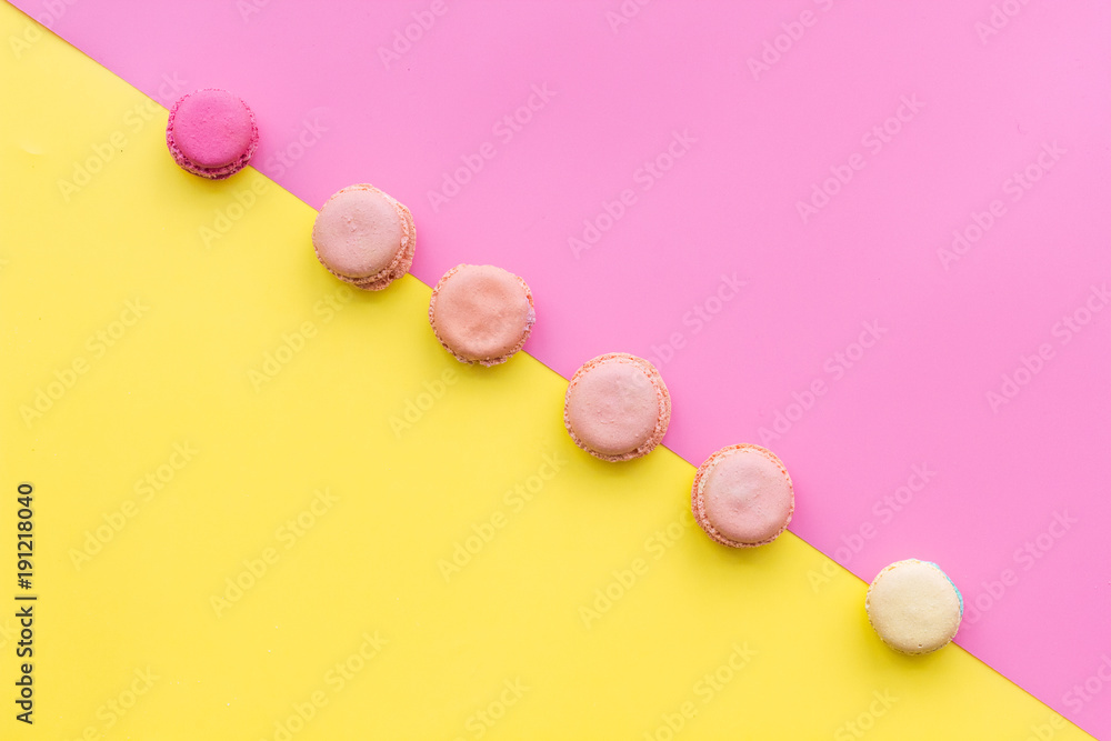 Macarons dessert. Pattern on yellow and pink pastel background top view copy space